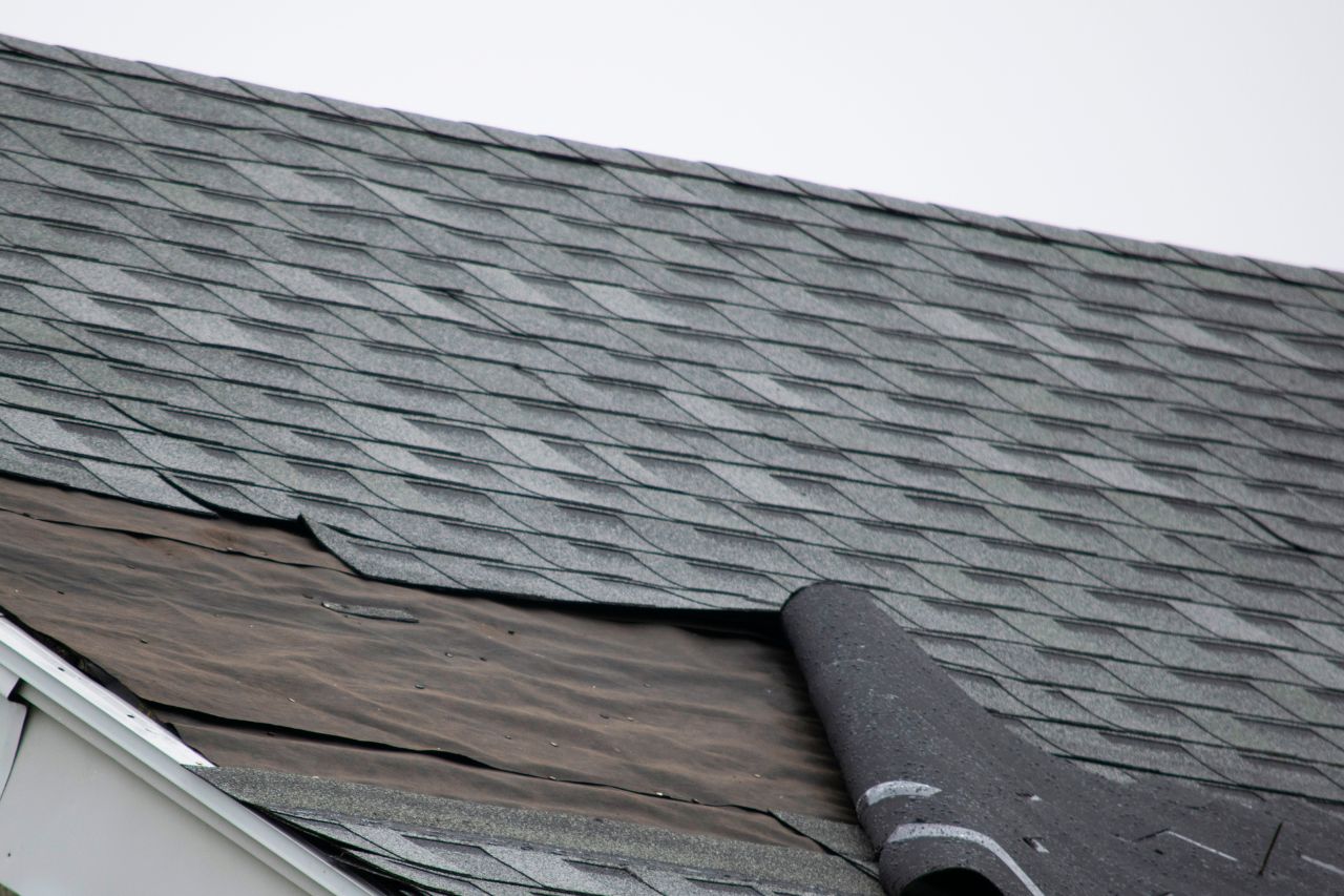 Close-up view of a roof with missing shingles and exposed underlayment, highlighting the need for professional roofing repair services.