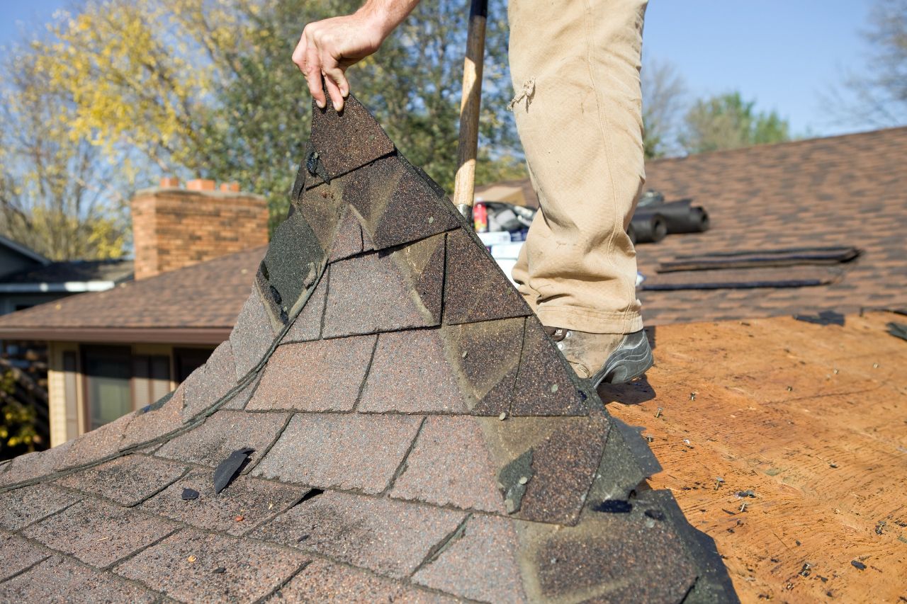 Professional roofer removing worn and damaged shingles during a roof replacement project in Metro Detroit ensuring a durable and weather-resistant result.